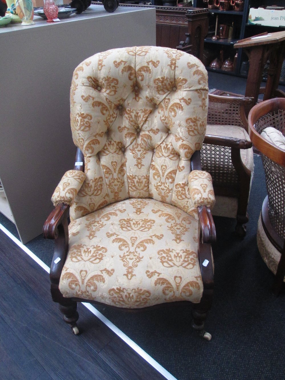 A late Victorian mahogany frame armchair, having later gold embossed upholstery on turned legs