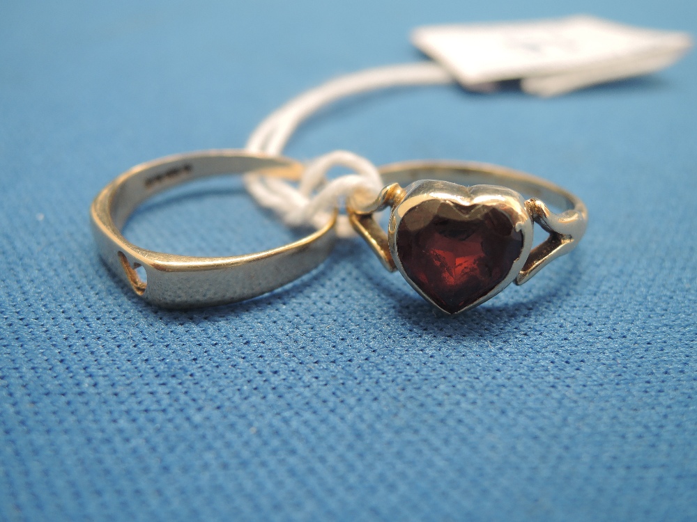 A ladies dress ring having a heart shaped garnet style stone on a 9ct gold loop and a 9ct gold band