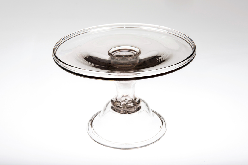 AN EARLY 18th CENTURY GLASS TAZZA OR WAITER, the dished top above an inverted baluster stem,