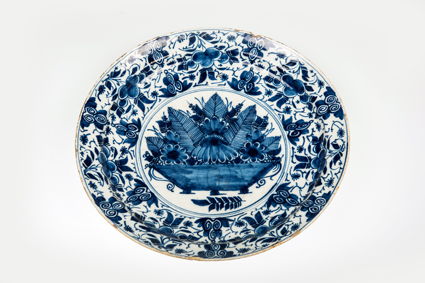 AN 18th CENTURY DUTCH DELFT BLUE AND WHITE CHARGER, the well painted with a bowl of flowers within a