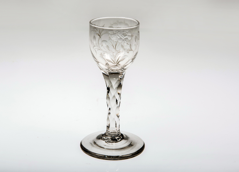 AN 18th CENTURY WINE GLASS, the cut and etched bowl on a facet-cut stem and domed circular foot.