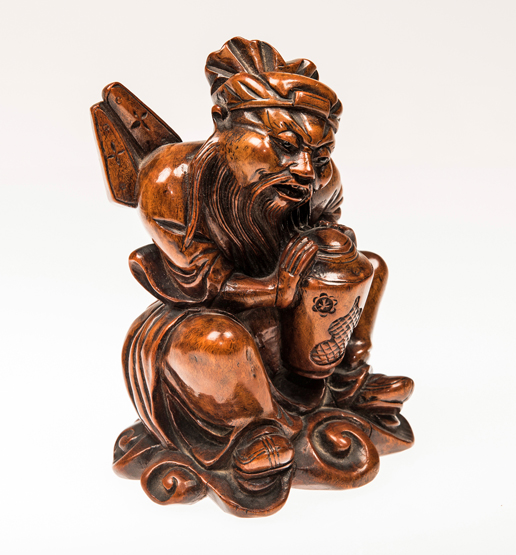 A CHINESE ROOTWOOD CARVING, 19th CENTURY, the seated man holding a covered vase. 17cm