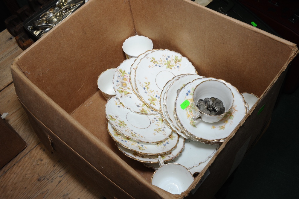 A box comprising a floral decorated tea service and a quantity of threepenny bits.