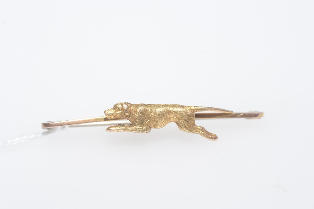 An (unmarked) gold bar brooch mounted with a running hound, late 19th century. Length 52mm