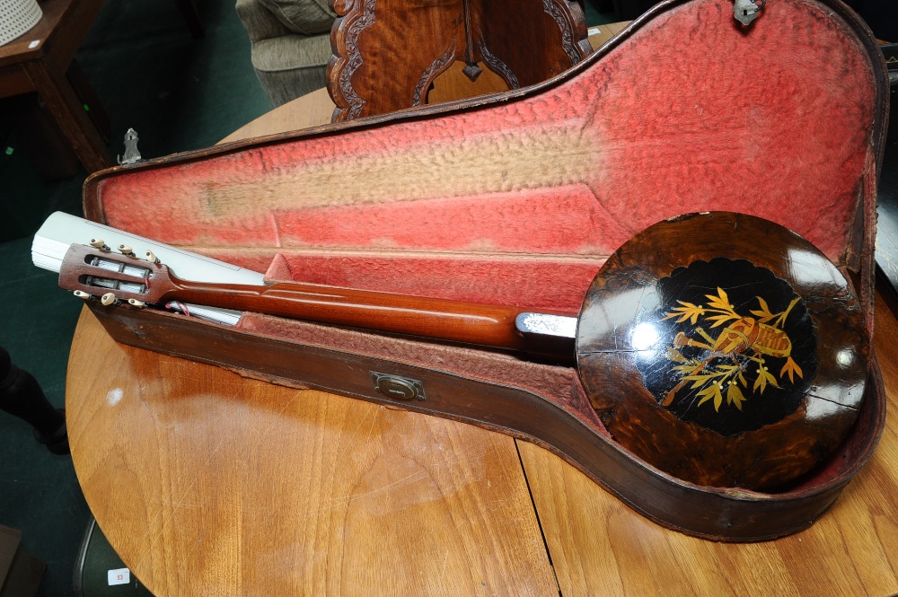 A marquetry inlaid four string banjo in a hard leather case.