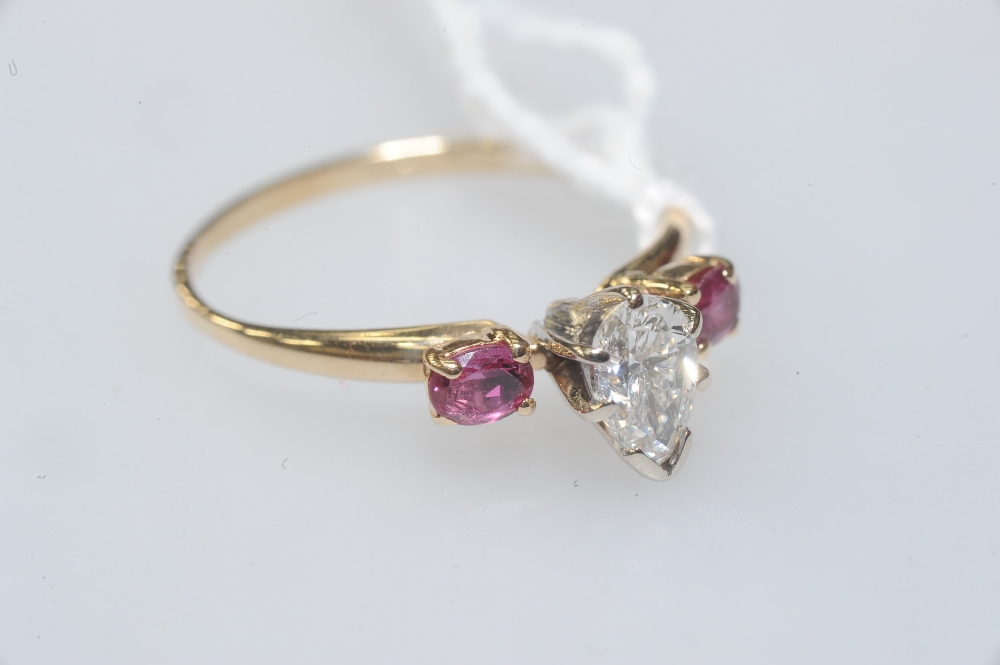 A diamond and ruby three-stone ring, the pear-cut diamond flanked by a pair of round-cut rubies, all