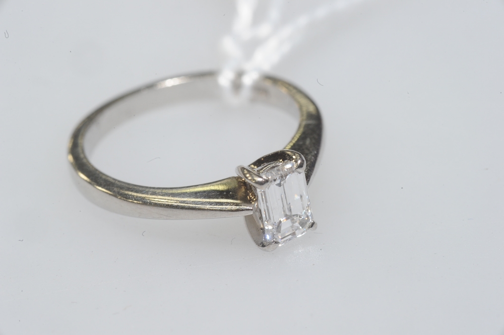 An emerald-cut diamond solitaire ring, the stone claw-set on a platinum band. Diamond approx. 0.33