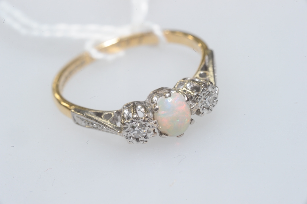 An opal and diamond three-stone ring, the oval cut opal flanked by a pair of brilliant-cut diamonds,