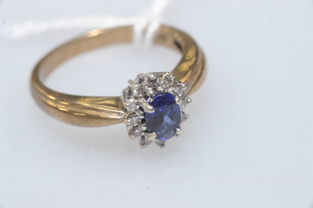 A sapphire and diamond cluster ring, the oval-cut sapphire within a band of brilliant-cut