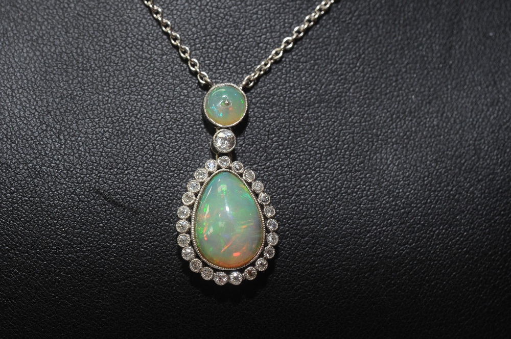 An opal and diamond pendant, the pear-cut opal within a bezel of brilliant-cut diamonds, beneath a