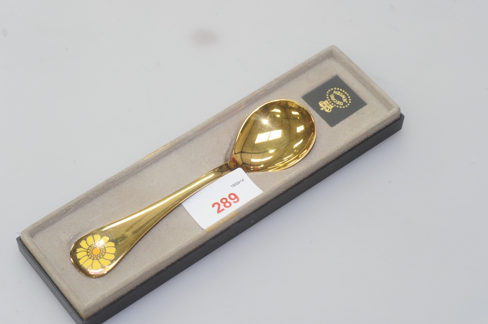 A Georg Jensen silver gilt spoon, boxed, the finial decorated with yellow enamel flower head and