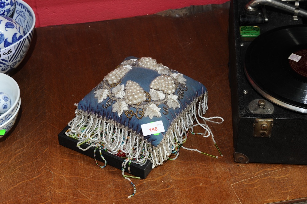 A group of late 19th/early 20th century beadwork comprising a large pin cushion and two hanging
