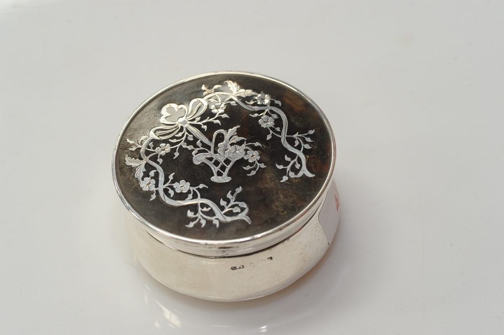 A circular silver and tortoiseshell box, the cover decorated in silver with a garland of flowers,