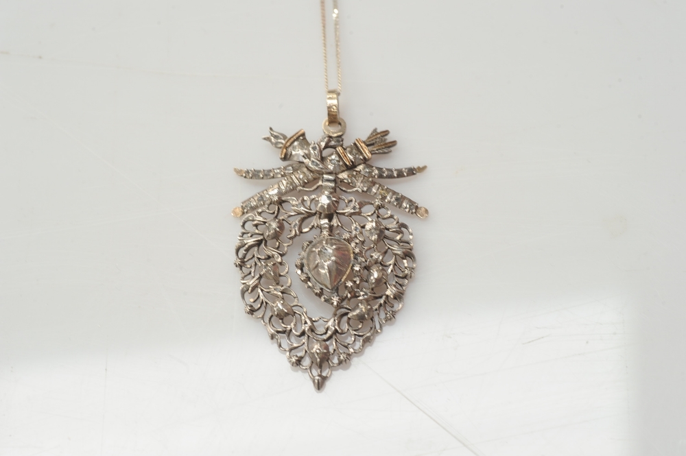 A silver and diamond pendant, circa 1800, the heart shaped mount pierced with foliate decoration set