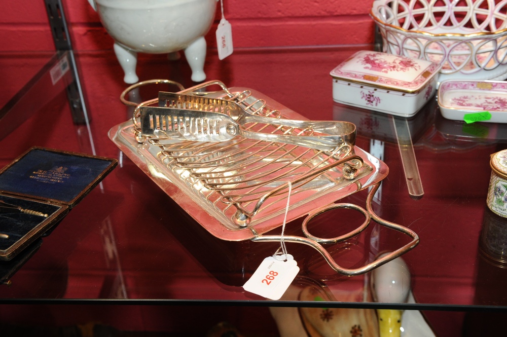 A silver-plated asparagus tray and tongs, twin handled and raised on bun feet.