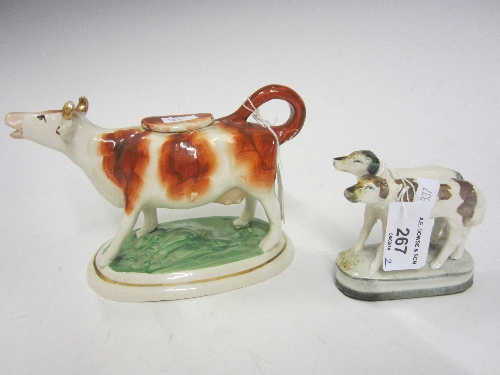 A STAFFORDSHIRE COW CREAMER, oval base, 12cm. and a Staffordshire group of two hounds. (2)