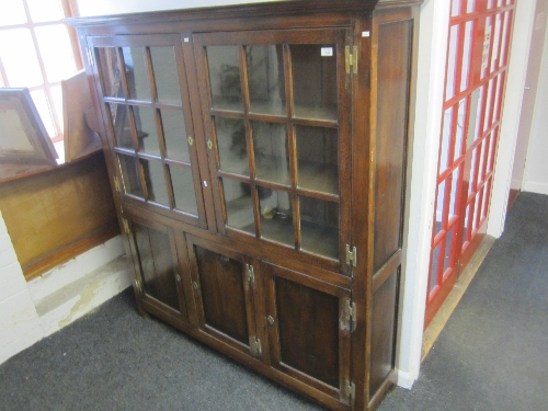 AN OAK SIDE CABINET with two nine pane glazed panelled doors, the upper section enclosing two