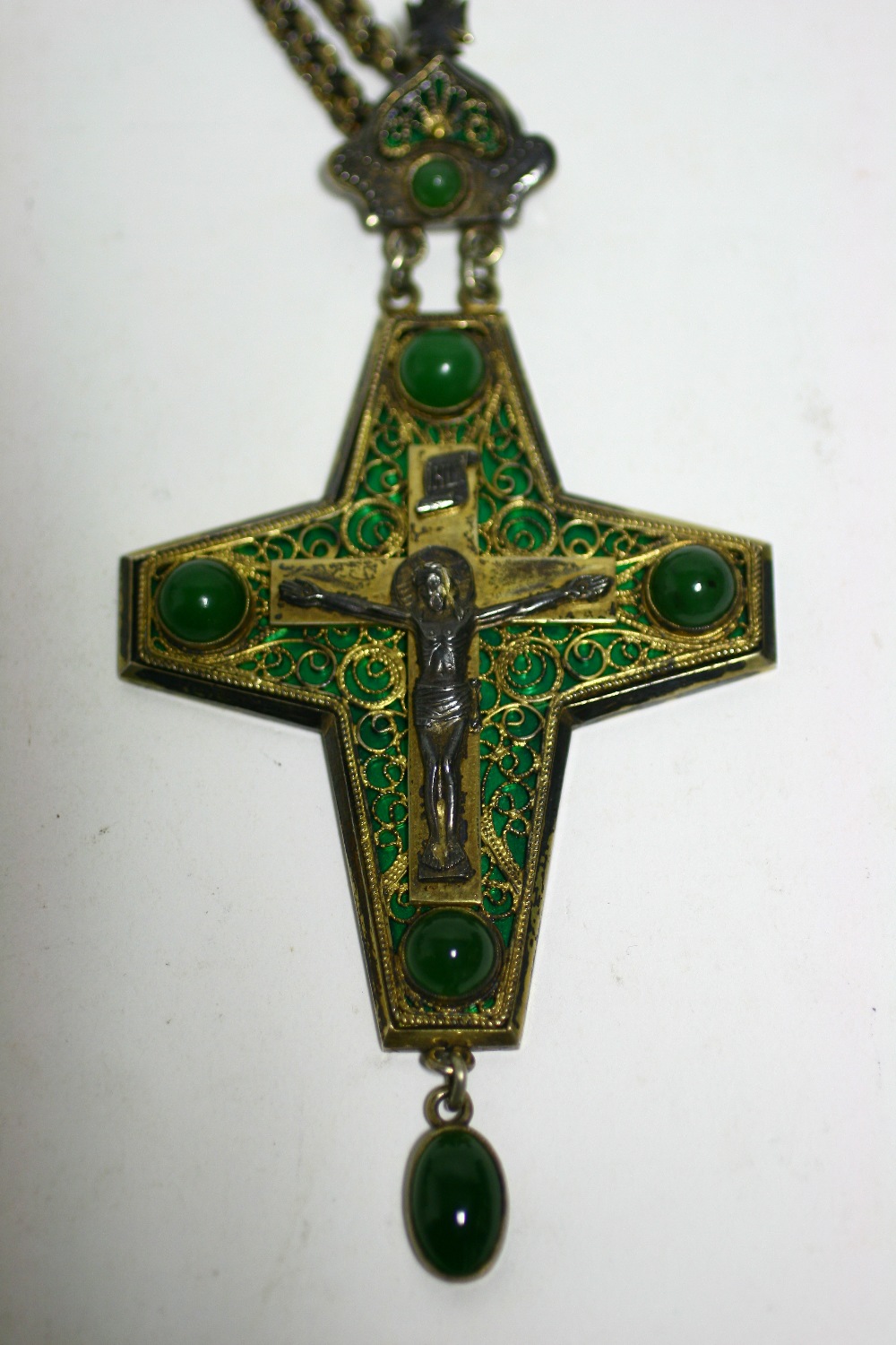 A Russian silver-gilt & green enamel pendant crucifix with filigree decoration & inset four green