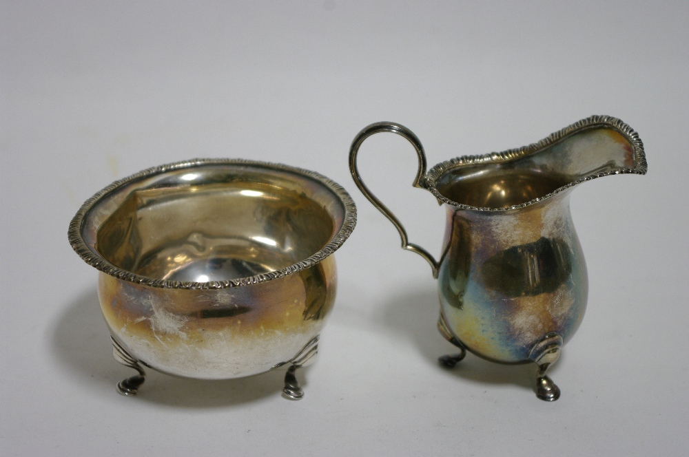 A small baluster cream jug & matching circular sugar bowl, each with gadrooned rim & on three pad