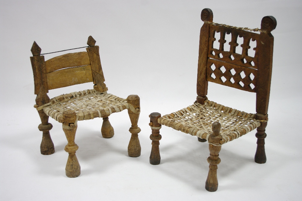 Two African carved hardwood chairs, each with woven hide seat.
