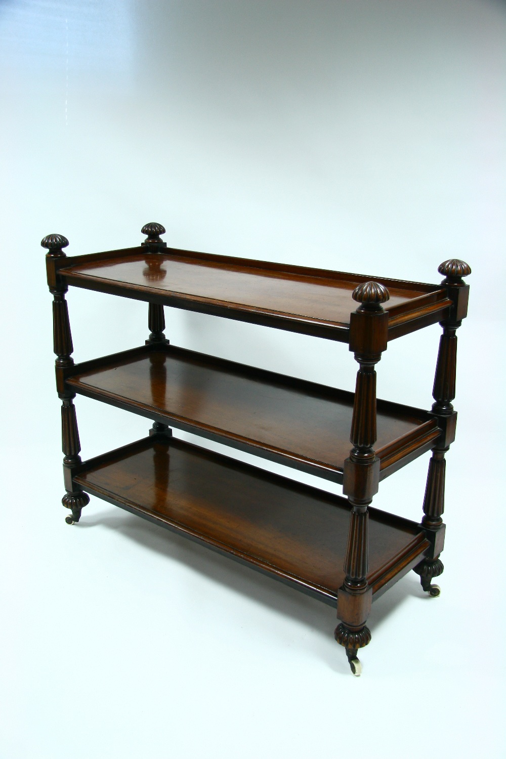 A Victorian mahogany three-tier dumb waiter with reeded tapered supports, finials, & bun feet with