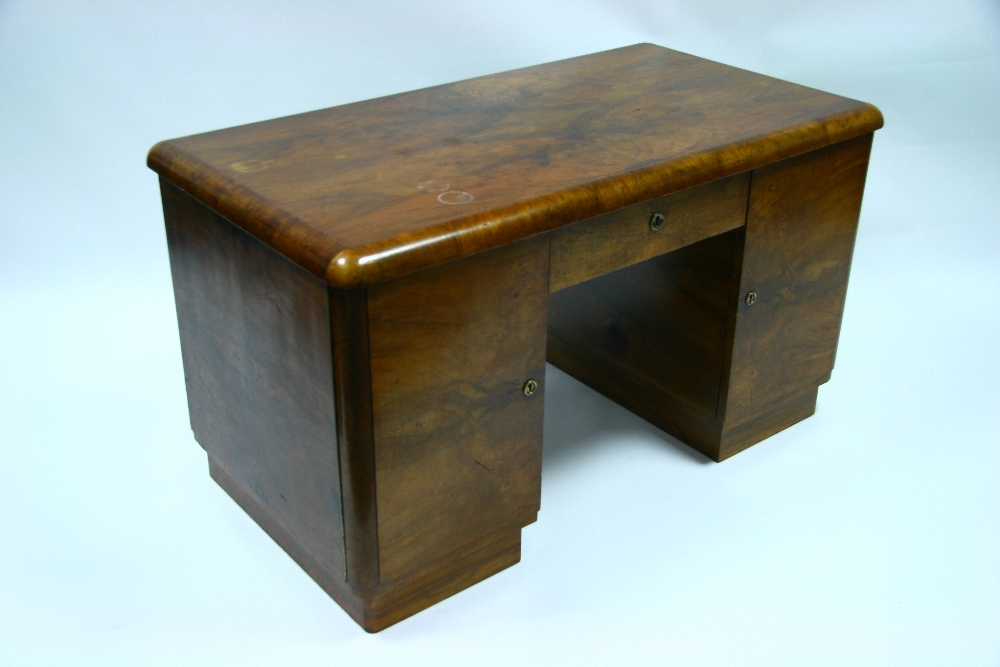 A 1930?s figured walnut pedestal desk fitted centre frieze drawer, a cupboard to the left, sliding