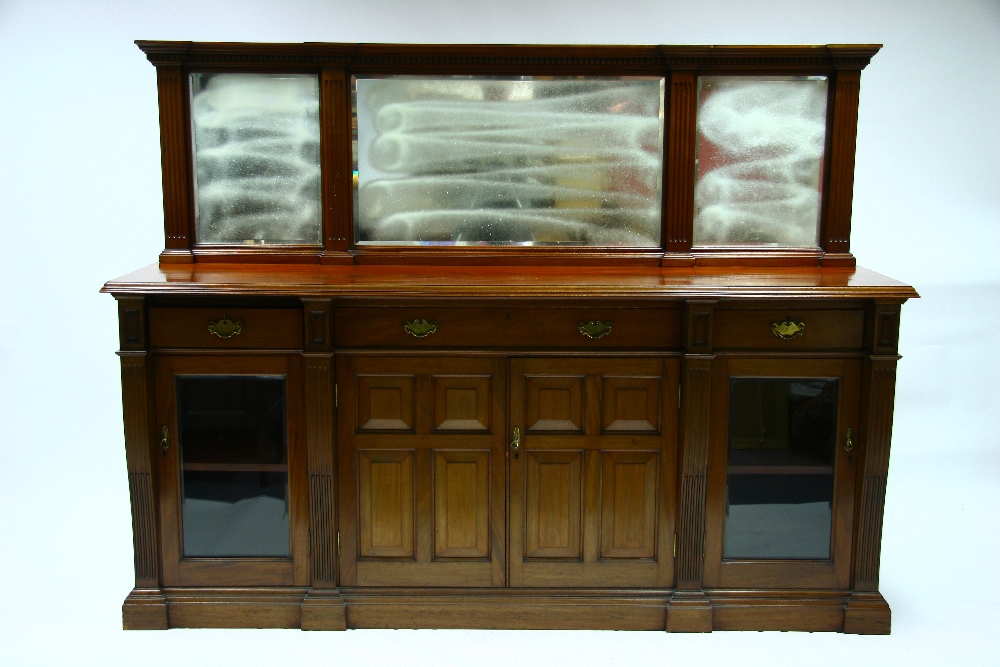 A late Victorian mahogany sideboard, the low mirrored back inset three rectangular bevelled plates,