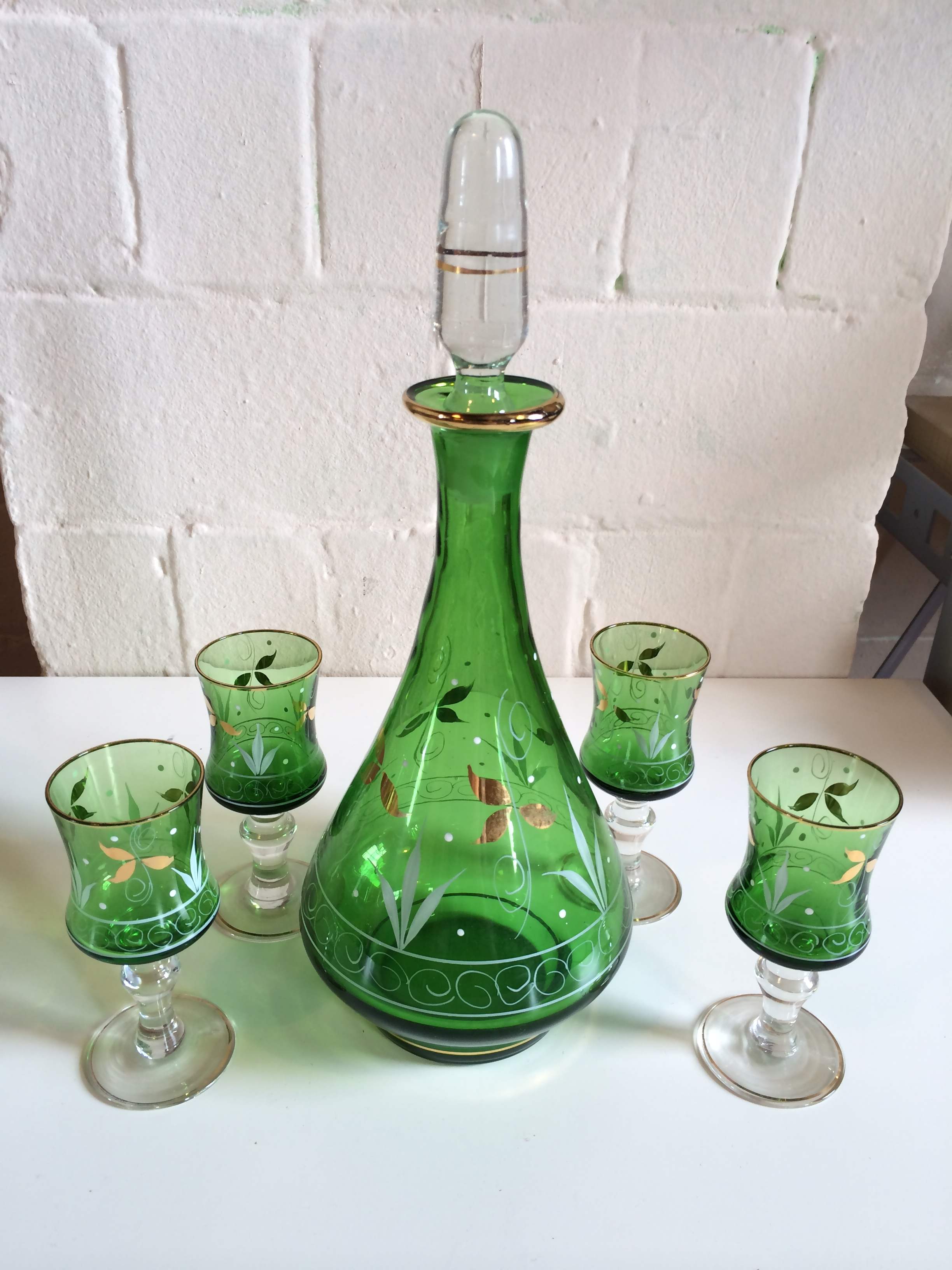 Green glass decanter with white and gold colour decoration and 4 matching glasses.