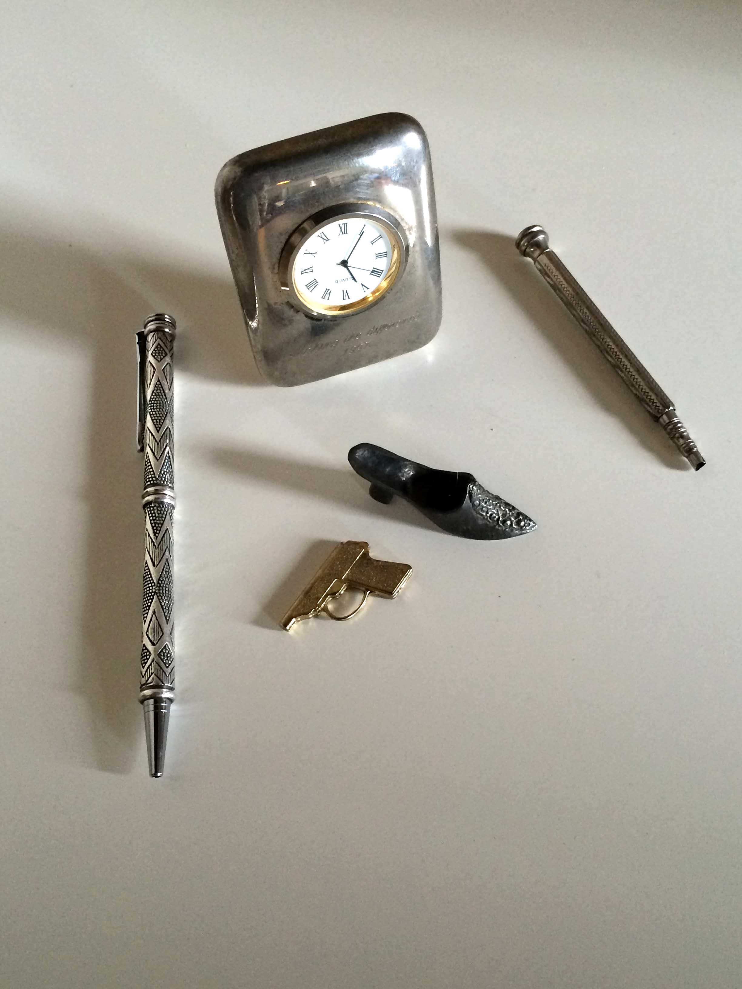 Gold colour metal gun, Pewter shoe pin cushion, solid plated quartz desk clock and retractable