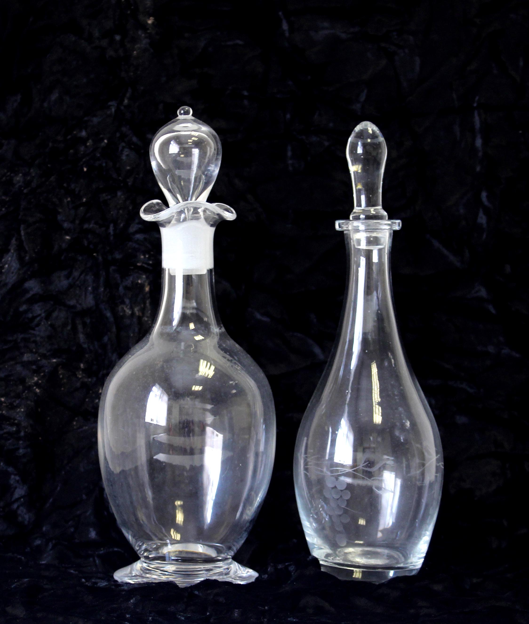 2 glass decanters with stoppers one having an etched grape design 27cm
