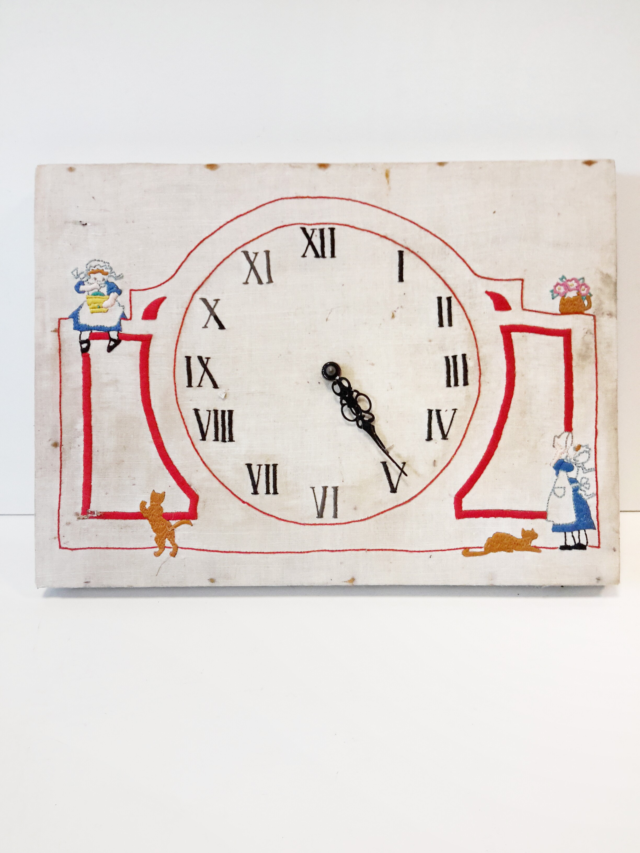 An unusual rustic clock made from an embroidered framed linen fabric.