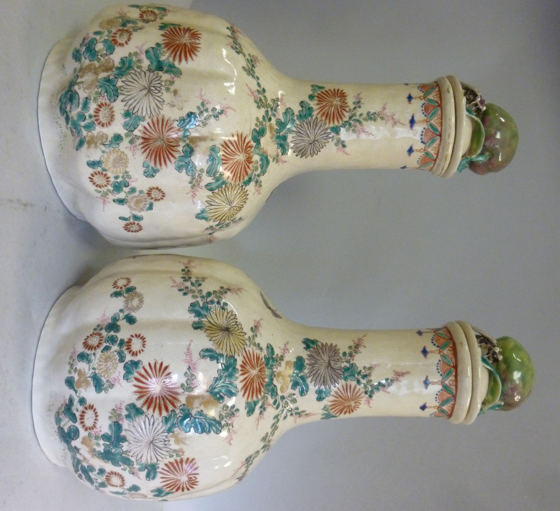 A pair of early 20thC Satsuma cream glazed earthenware bottle vases, the covers with moulded soft