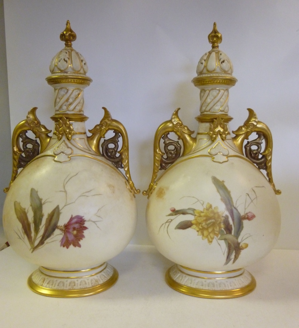 A pair of Royal Worcester china bottle vases, each having a narrow neck, flanked by mythical bird
