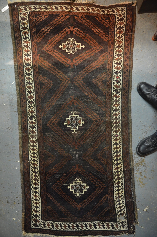 An old Belouch long rug, 2nd quarter 20th century, the geometric lozenge design on brown ground, 210