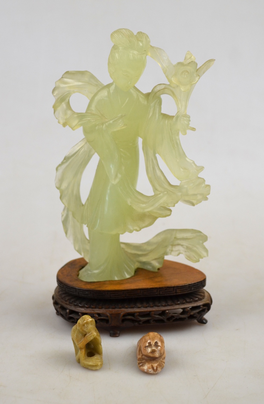 A Chinese green glass figure of a maiden holding flowers, 15.8 cm c/w a hardwood stand to/w two