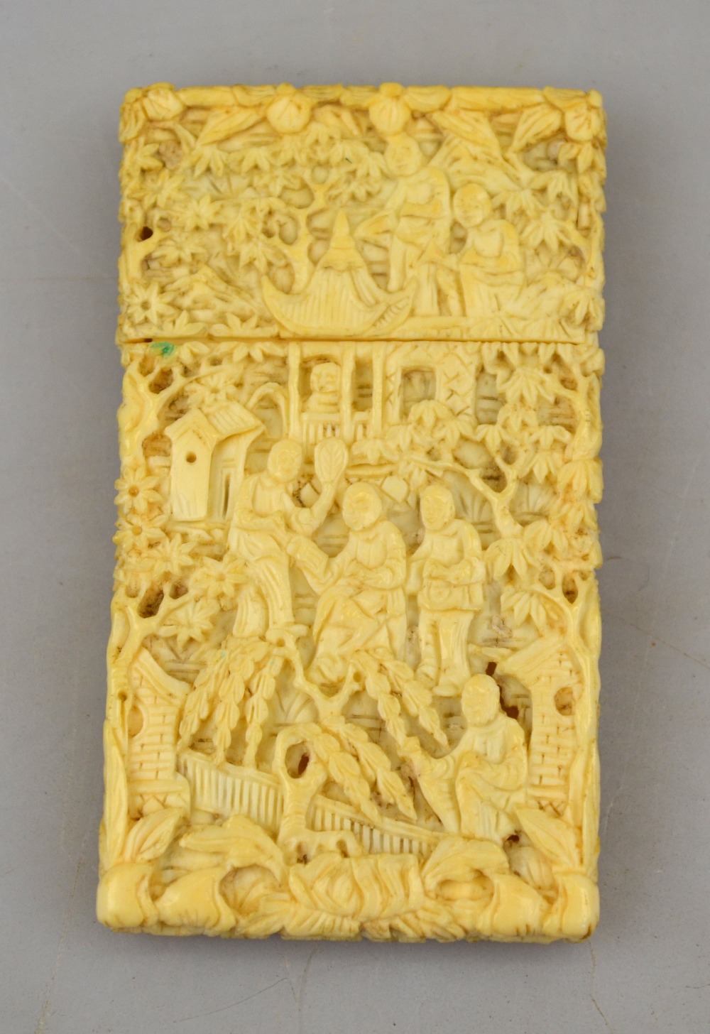 A Chinese Canton ivory card case carved with figures in buildings and under trees, 7.3 cm x 4 cm,