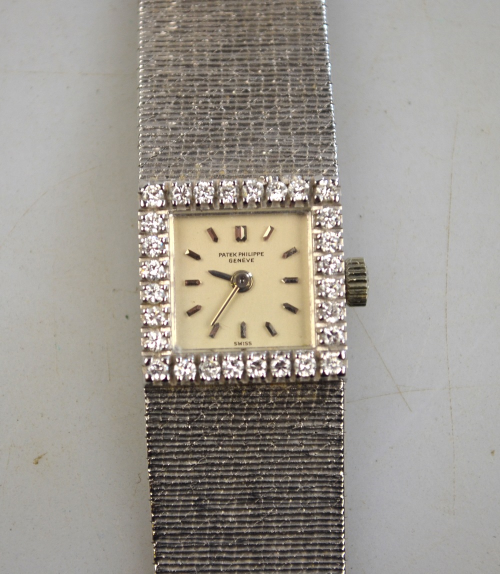 A Patek Phillipe lady`s platinum wristwatch with 11 mm square silvered dial and diamond-set bezel,