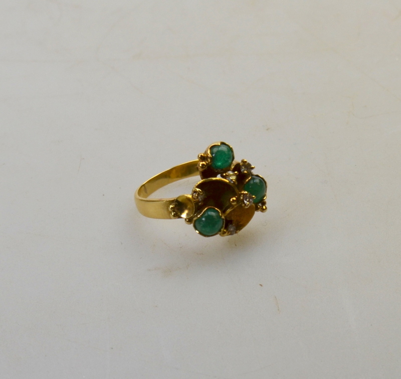 A ring to match lots 276 and 270, formed of textured craters inset with cabochon emeralds and