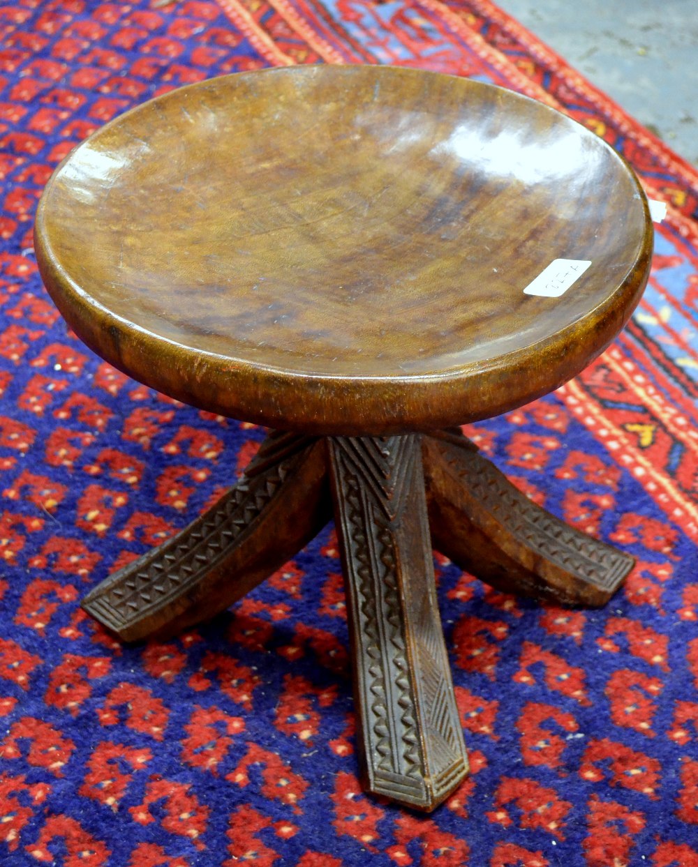 An African Yarouba carved wood stool having a dished circular seat raised on four outswept legs with