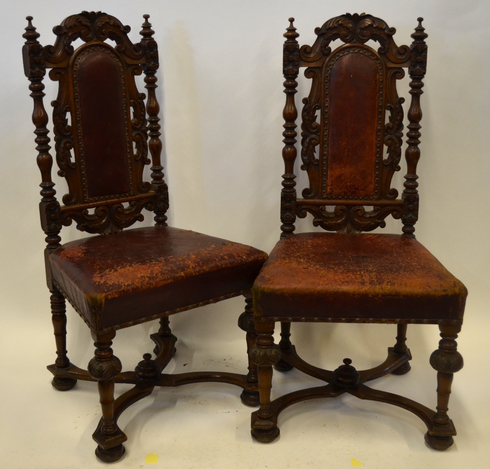 A pair of 19th century continental carved oak hall chairs with original battered red leather