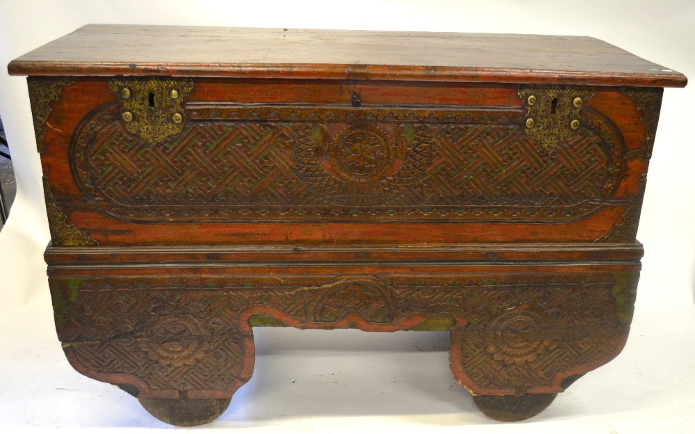 A large carved teak trunk on trolley wheels, traces of original polychrome decoration, 101 cm high x