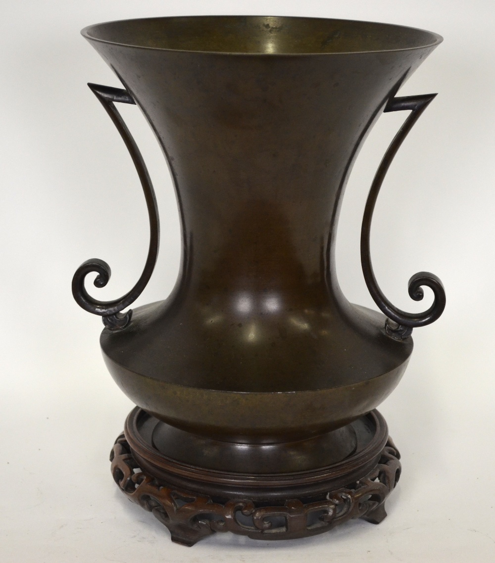 A Japanese bronze vase, the disk shaped body with tall splayed waisted neck and two scroll side