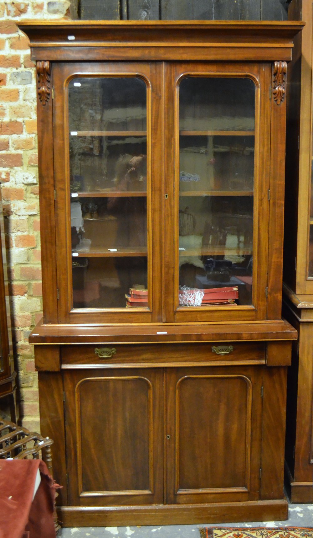 A small late 19th century mahogany chiffonier bookcase having a pair of glazed panel doors over a