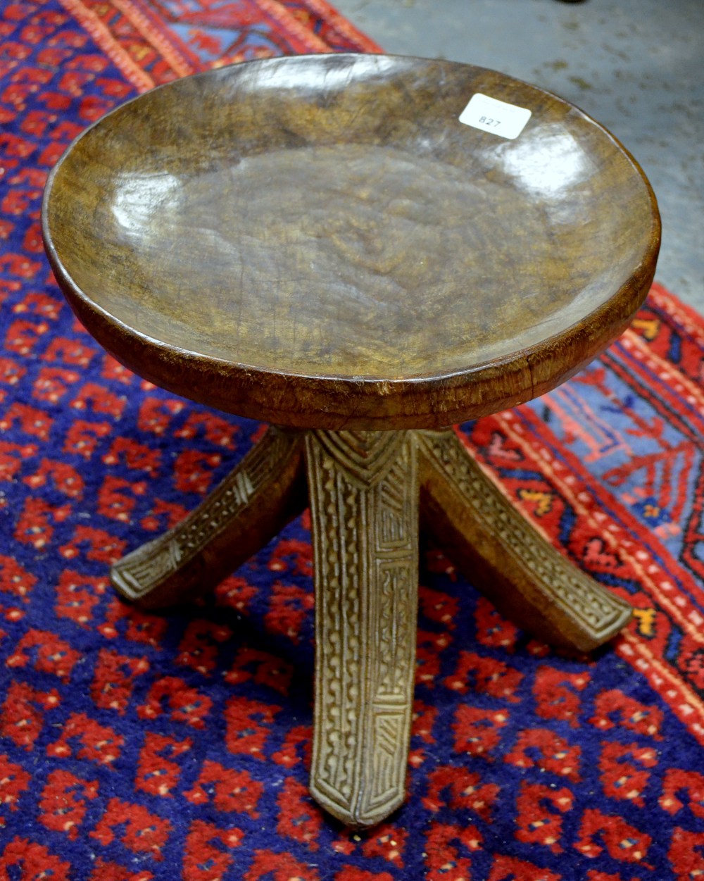 An African Yarouba carved wood stool having a dished circular seat raised on four outswept legs with