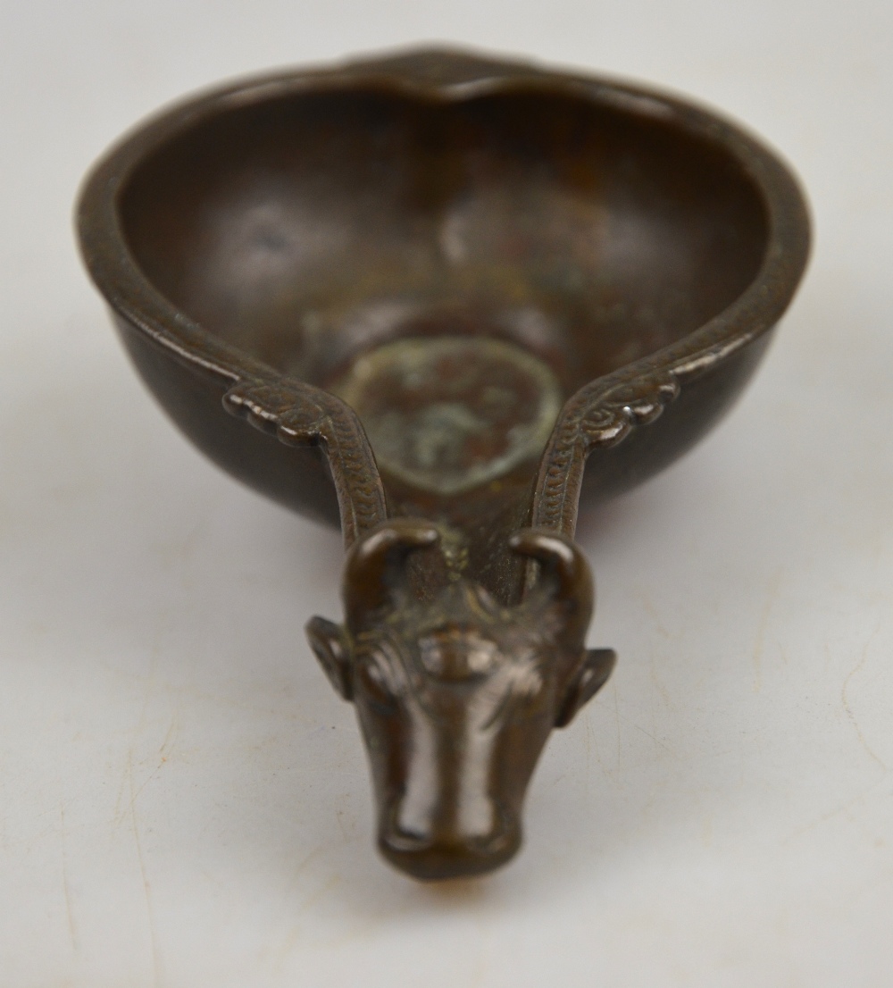 An Indian (?) bronze oil lamp, the spout cast as a cow's head