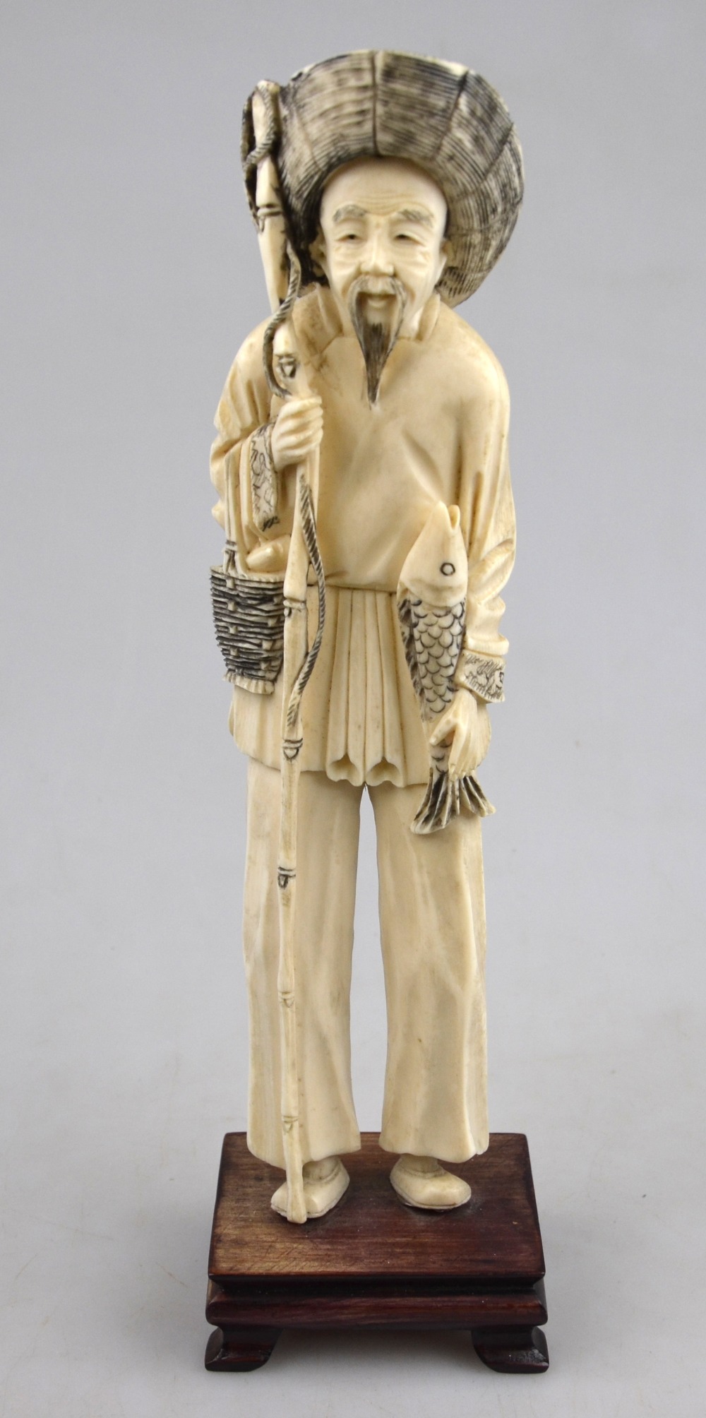 A Chinese late 19th/early 20th century ivory carving of a fisherman holding a fishing line in one