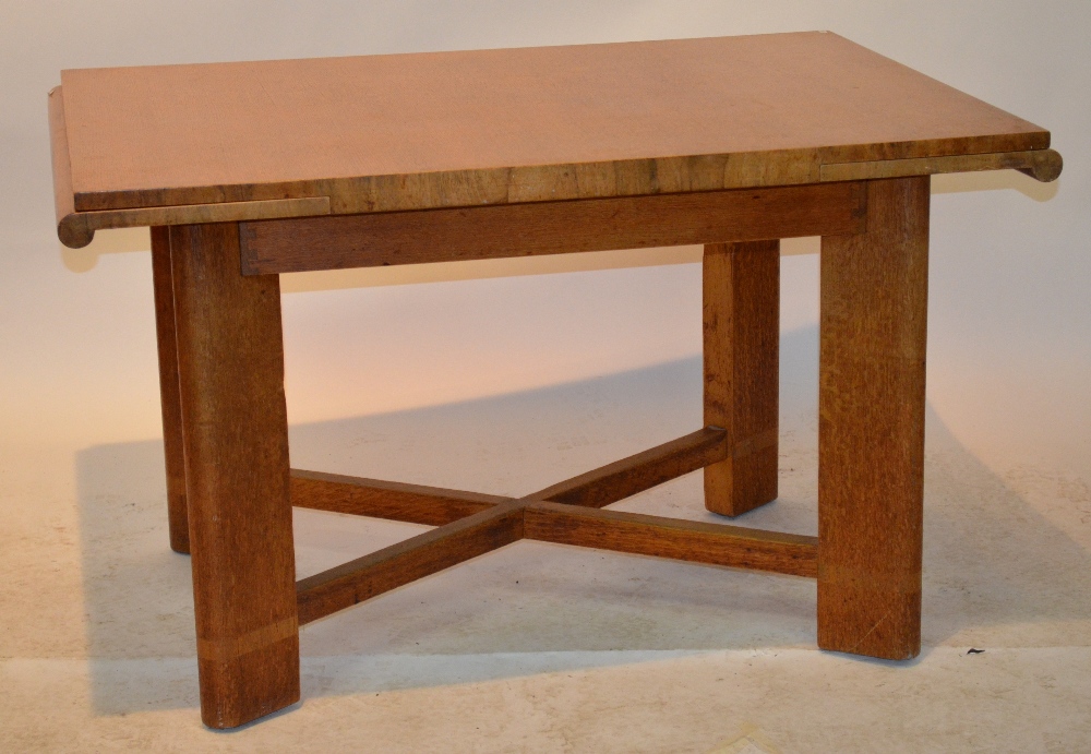An Art Deco period oak draw-leaf dining table raised on four angled legs united by square cross-