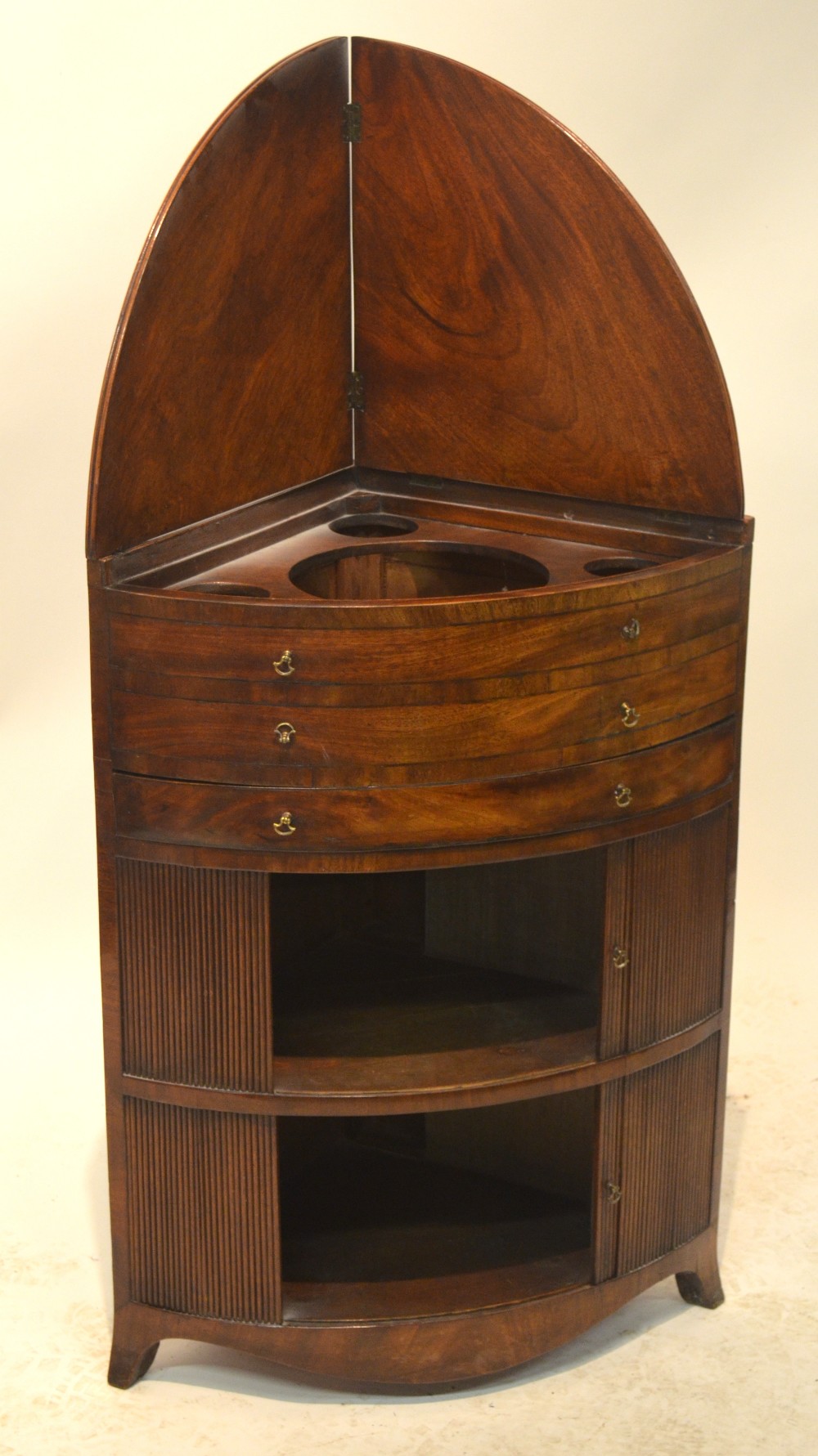 A 19th century mahogany corner washstand of bow front form, the rising top hinged to form a