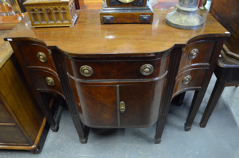 A compact Georgian style mahogany serpentine form sideboard, the top with raised brass splash rail