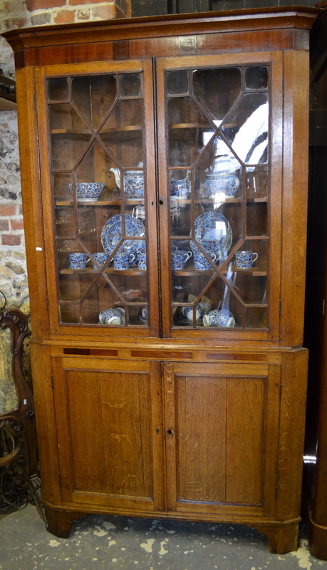 A George III oak astragal glazed corner cabinet in two parts, the upper with pair of doors